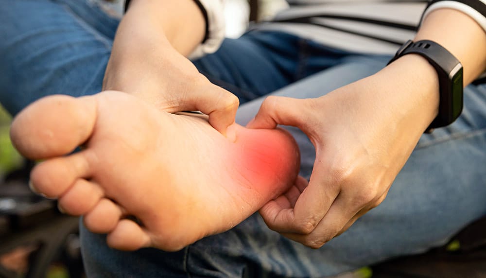 woman holding her heel in pain due to plantar fasciitis